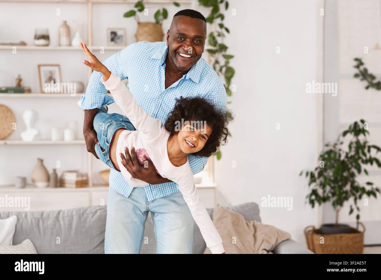 Divertimento in famiglia. Felice nonno afroamericano che gioca a stupido gioco con sua nipote a casa, spazio vuoto Foto Stock