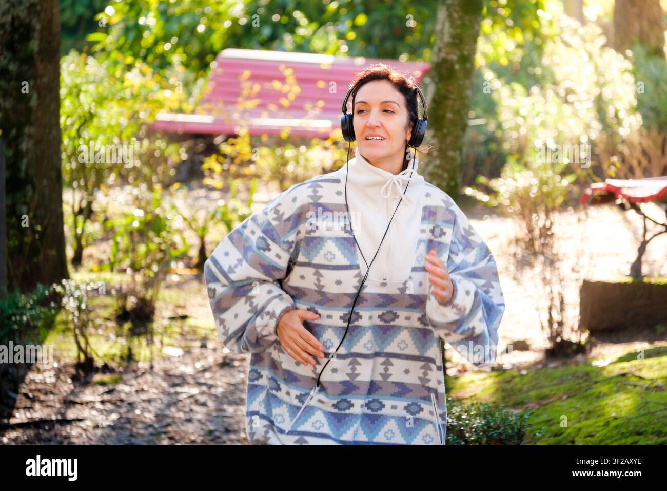 Donna che godersi uno stile di vita sano mentre fa esercizio in un parco con le cuffie Foto Stock