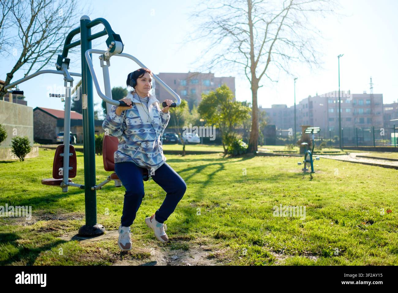 Donna che esegue un allenamento su attrezzature fitness all'aperto in un parco soleggiato Foto Stock