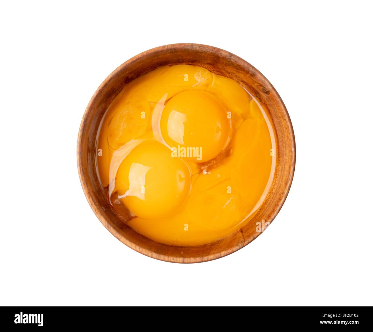 Tuorli d'uovo sbattuti in una ciotola, uova di pollo fresche per ricetta di cucina, tuorli organici mischiati in una ciotola di legno Foto Stock