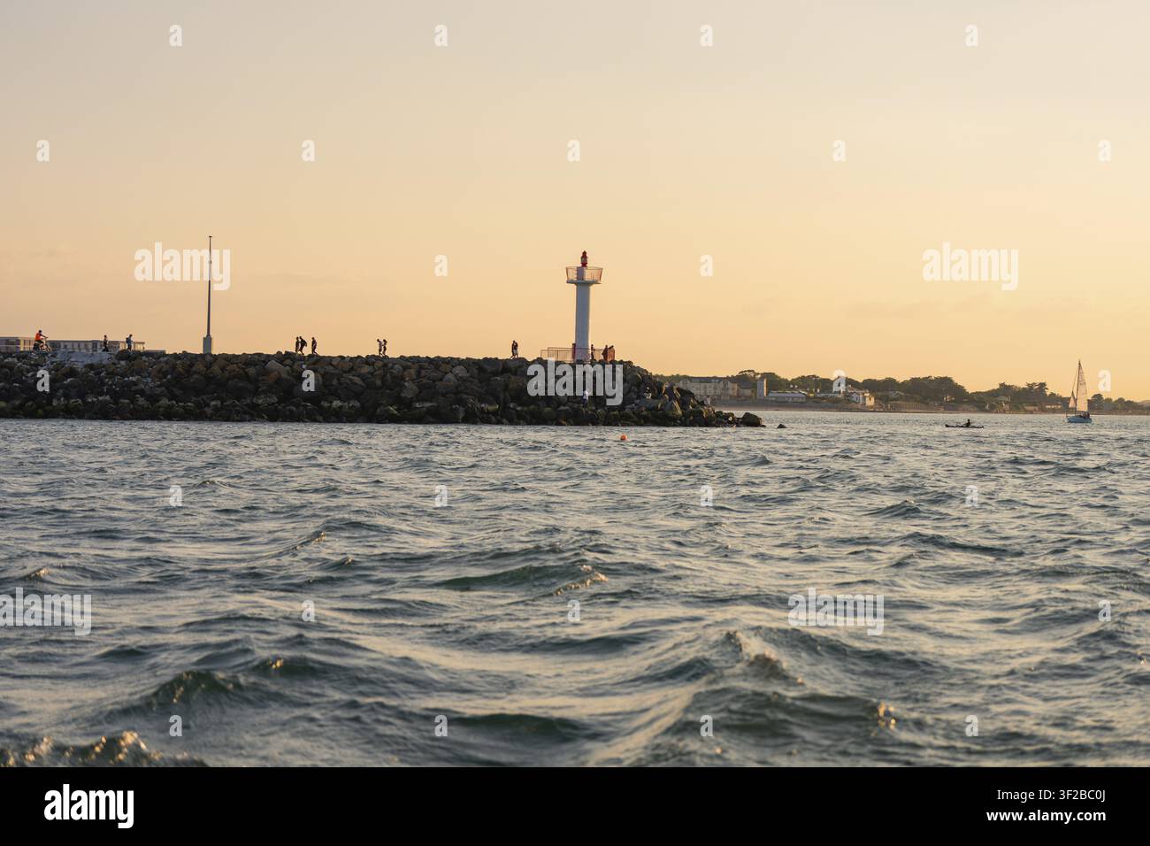 Faro e riva rocciosa durante il tramonto, atmosfera calma, Howth, Irlanda Foto Stock
