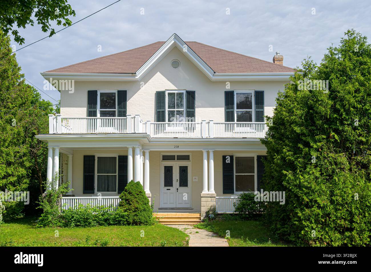 Grande casa bianca con portico, balcone e alberi. Foto Stock