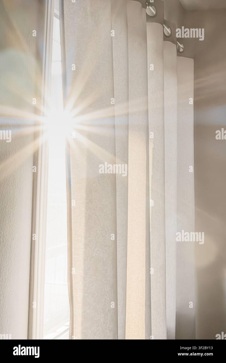 Bellissimo sfondo estetico di luce mattutina brillante con flare della lente che filtra attraverso tende tessili su una finestra. Interno di casa accogliente e tranquillo Foto Stock