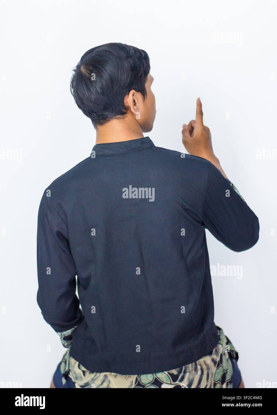 Ritratto di vista posteriore di un uomo asiatico che indossa una tradizionale camicia fusion in batik isolata su sfondo blu. Foto Stock