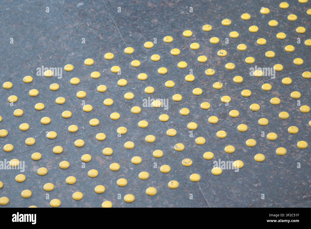 Pavimentazione tattile gialla su un marciapiede per la guida alla sicurezza Foto Stock