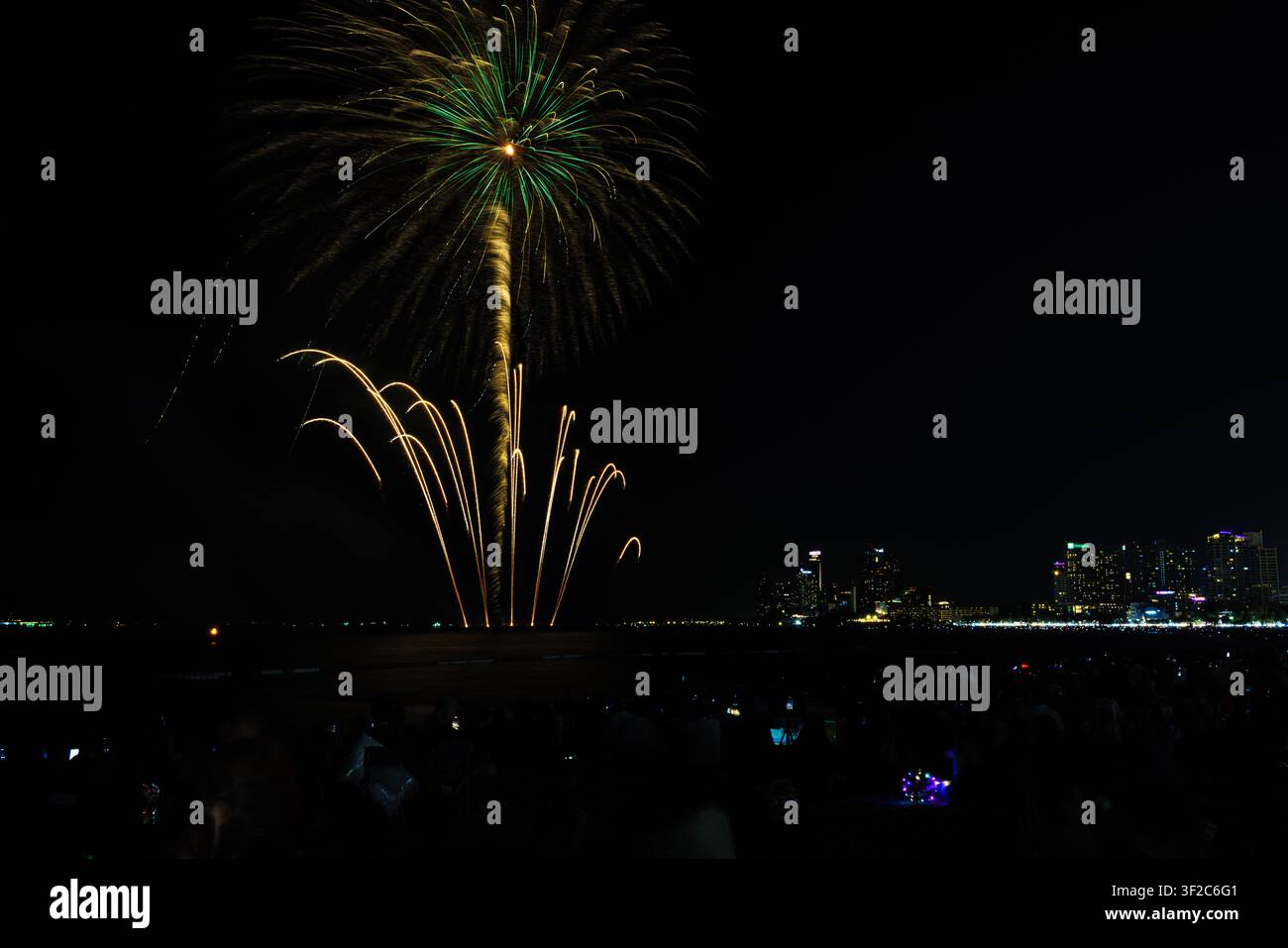 Uno spettacolo di fuochi d'artificio vivace illumina lo skyline di una città costiera di notte creando un'atmosfera festosa per le campagne di marketing delle vacanze e del turismo. Foto Stock