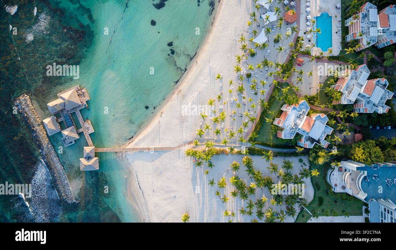 Vista aerea della località balneare con bungalow sull'acqua, sabbia bianca, palme e piscine a Juan Dolio, San Pedro de Macoris, Repubblica Dominicana Foto Stock