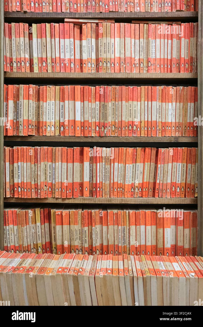 Scaffali di narrativa vintage Penguin con dorsi codificati arancioni Foto Stock