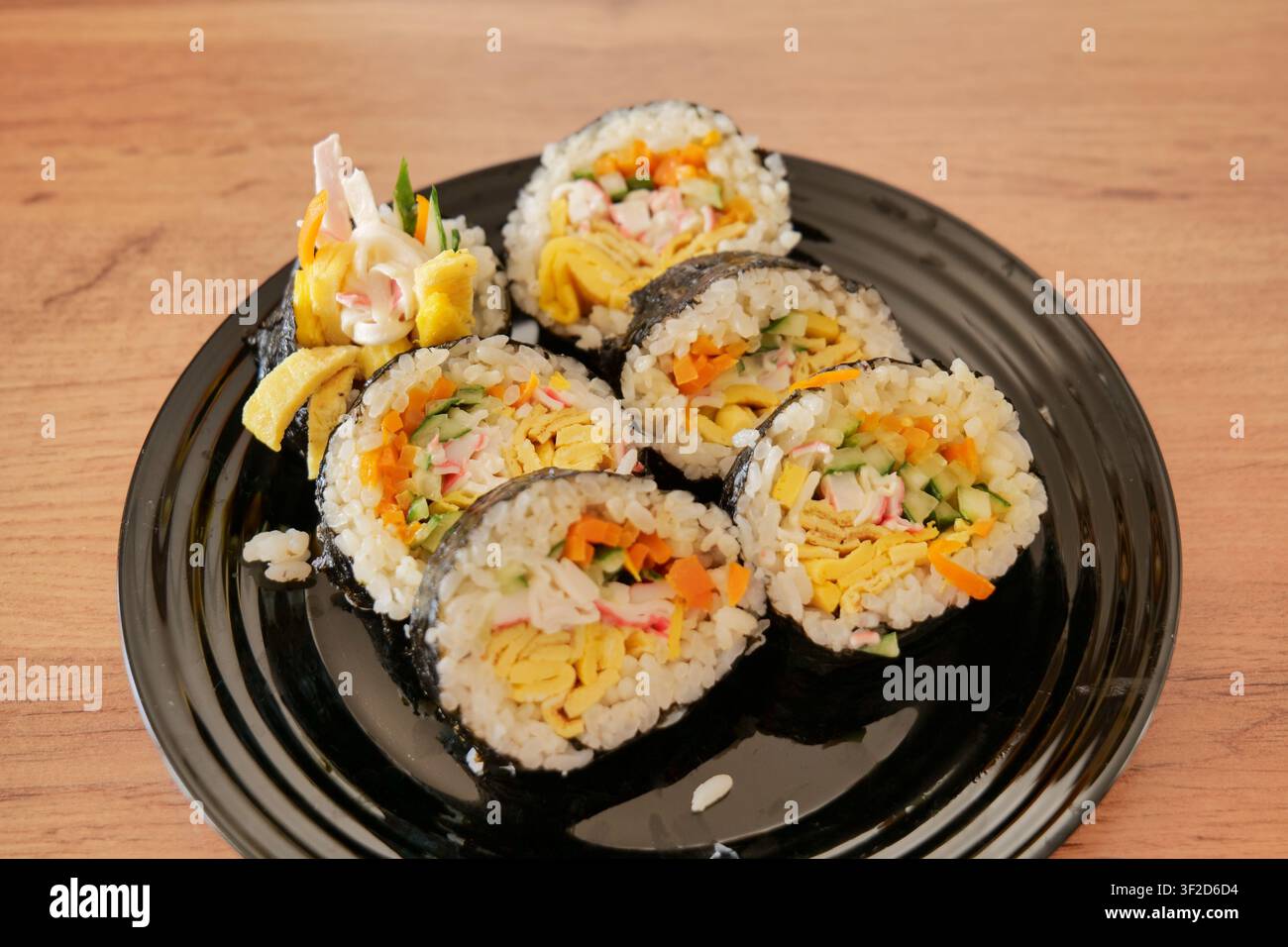 Kimbap fatto in casa affettato e servito su piatto nero Foto Stock