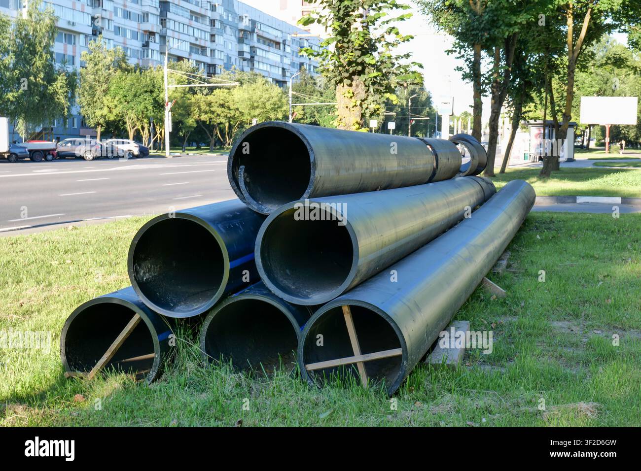 Grandi tubi neri sul marciapiede cittadino per lavori di costruzione Foto Stock