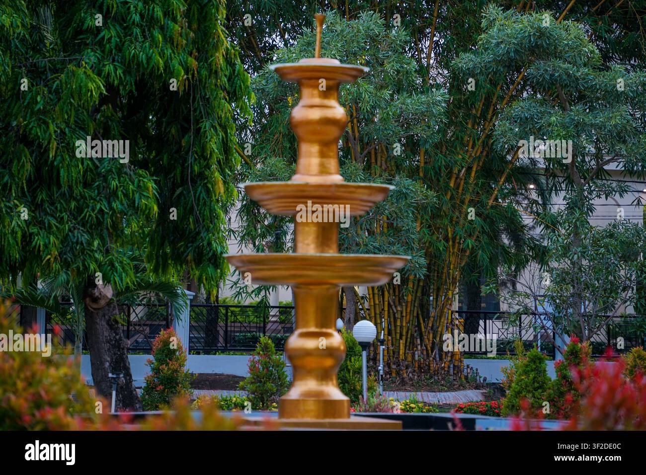 Scultura a più livelli di fontana dorata che si erge in un rigoglioso parco pubblico verde Foto Stock