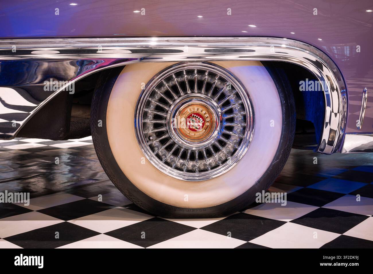Primo piano di una ruota in filo metallico classica della Cadillac Eldorado con pneumatico a fascia bianca larga e finiture cromate lucide del parafango. Foto Stock