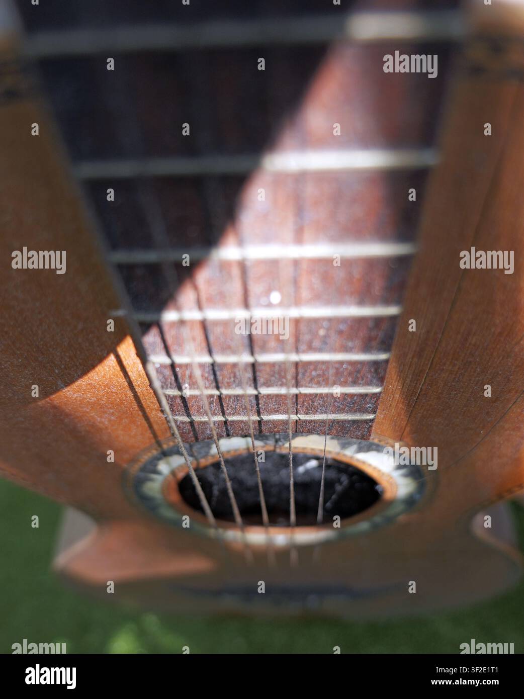 Mano della chitarra acustica, corde e rosone sotto la luce esterna. Cattura dei dettagli e della maestria dello strumento musicale. Bulgaria, Varna 14 luglio 2026 Foto Stock