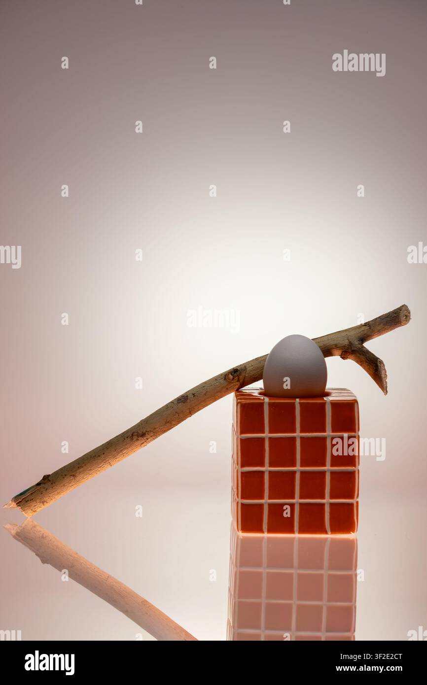 Natura morta concettuale con cubo a griglia rossa posizionato all'interno di una cornice triangolare in metallo su sfondo bianco. Interazione di forme geometriche, composizione minimalista in studio Foto Stock