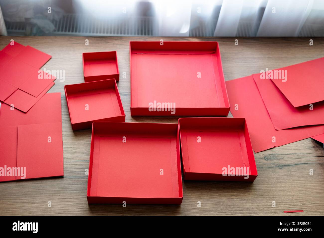 Coperchi di una scatola regalo pieghevole rossa raccolti su un tavolo di legno. Preparando una sorpresa. Foto Stock