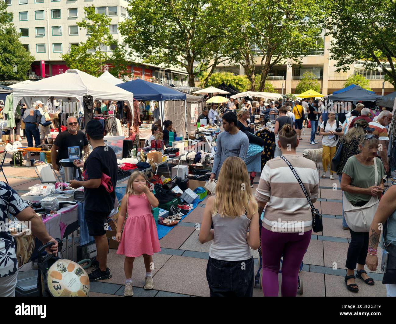 Pforzheim, Germania, 18 luglio 2026 Area del mercatino delle pulci con vari oggetti disposti su tavoli mentre i visitatori si muovono nello spazio presentando una scena neutra del quotidiano Foto Stock