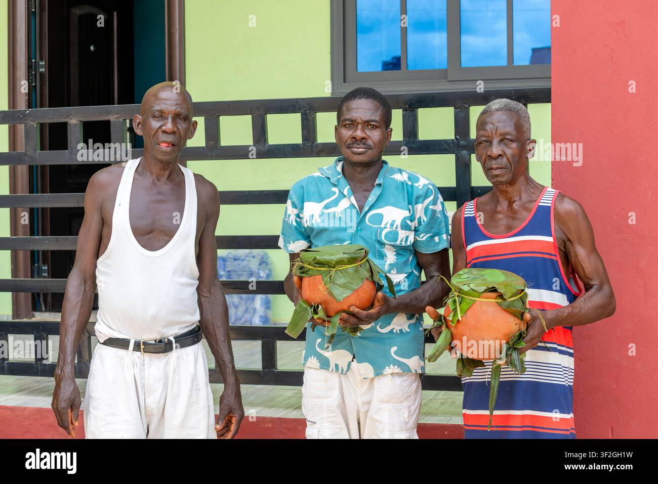 Uomini tengono vasi di argilla avvolti in foglie di banano, Somanya, Ghana Foto Stock