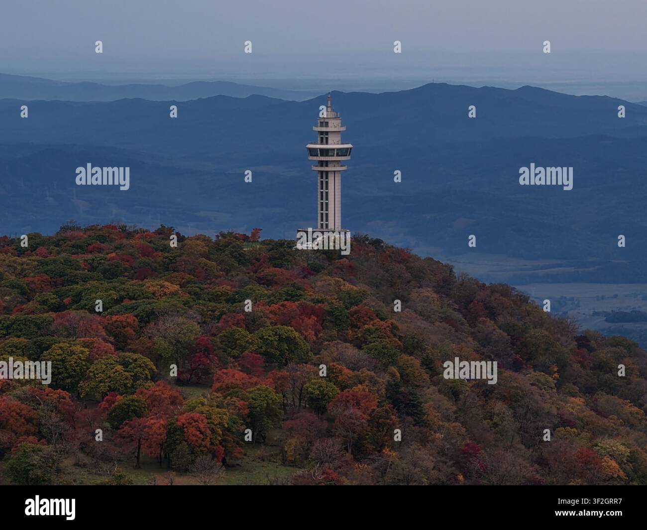 Una vista a teleobiettivo da drone attraverso le catene montuose della provincia di Jilin incornicia l'osservatorio bianco distintivo che si erge sopra una collina in fiamme Foto Stock