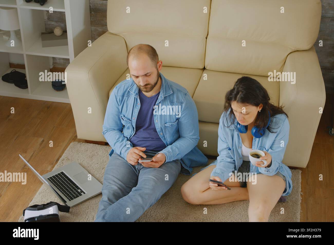 Coppia che si rilassa navigando su internet nel loro accogliente appartamento, con lavoro su laptop e dispositivo digitale, connettendo lavoro su laptop, dispositivo digitale e lavoro su computer. Foto Stock