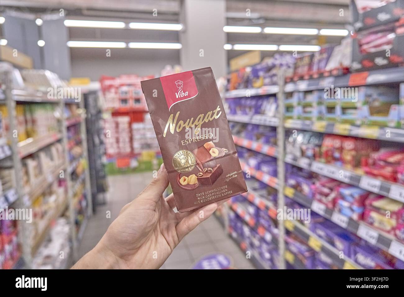 Mano che mostra un espresso al nougat Viba, confezione scura nel supermercato, illustrazione di un chicco di caffè espresso, prodotto, caramella, shopping, negozio, acquisto, dolce, caramella, super Foto Stock