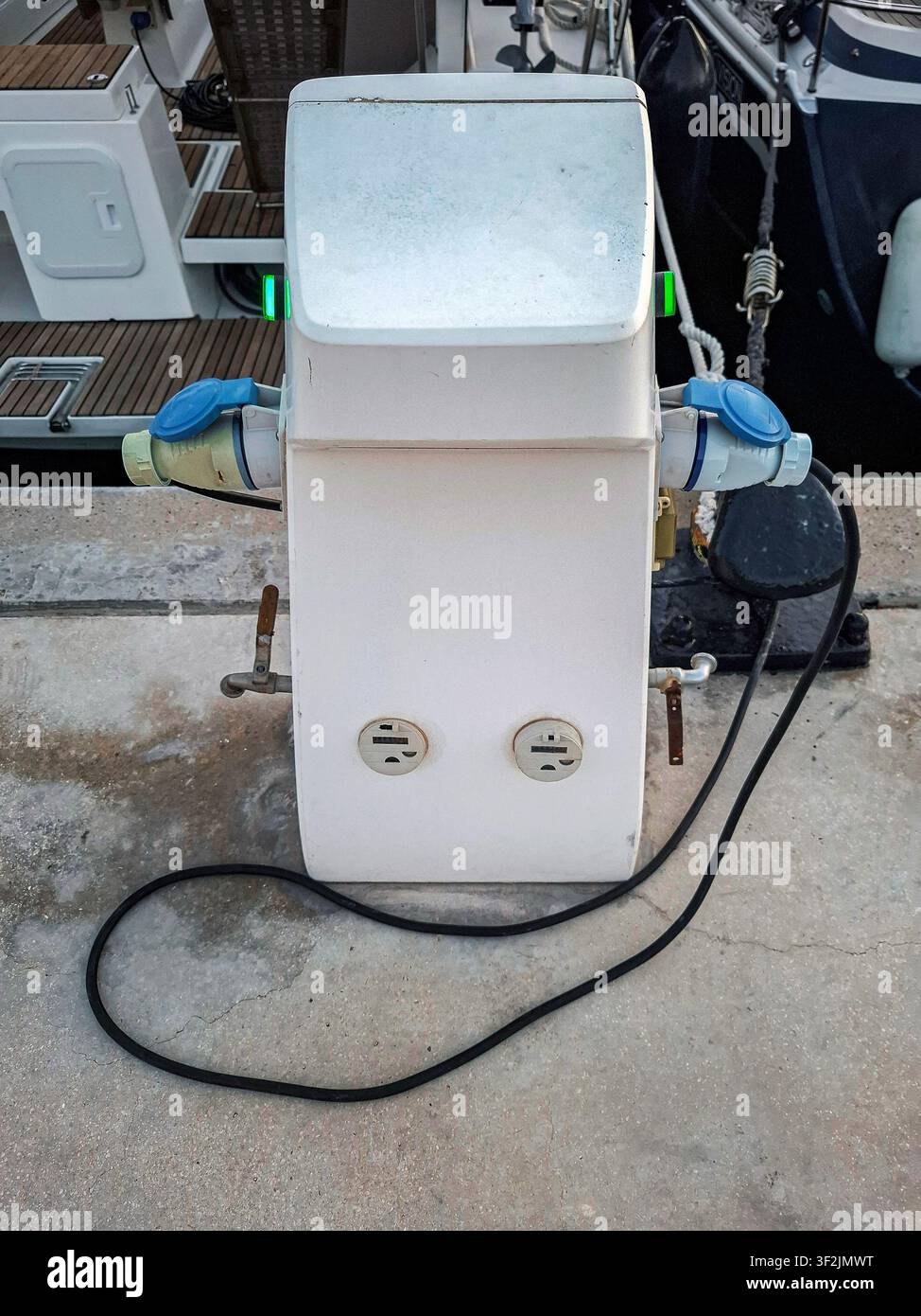 Una stazione di ricarica è posizionata accanto a un posto barca per yacht, fornendo collegamenti essenziali di alimentazione per le imbarcazioni. Questa configurazione facilita un comodo Foto Stock