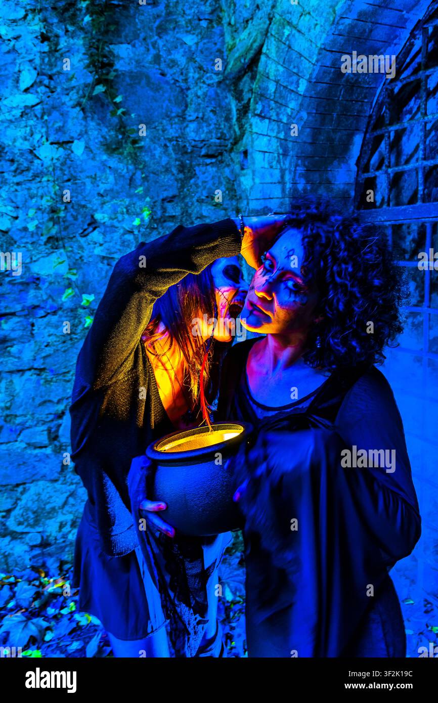 Vampiri e streghe che celebrano Halloween con una bevanda frizzante in un calderone Foto Stock