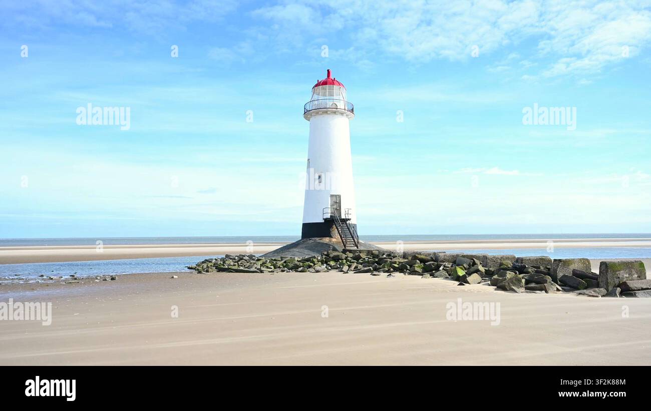 TALACRE, GALLES - 05 LUG 2024: Il faro di Point of Ayr si erge su una spiaggia sabbiosa circondata da rocce durante la bassa marea a Talacre, nel Galles del Nord. Foto Stock