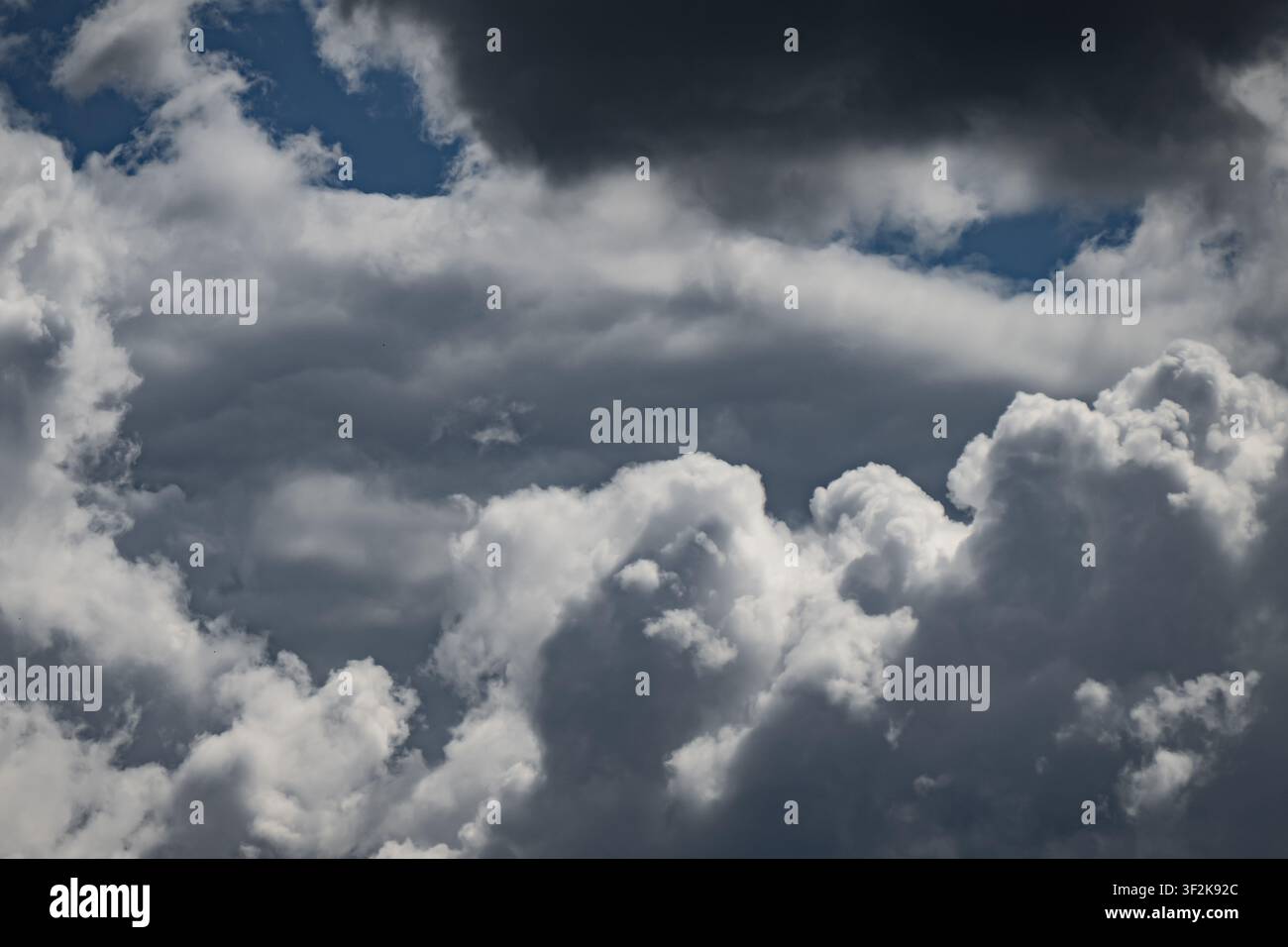 Nuvole minacciose che si agitano nel cielo azzurro mostrando dinamiche atmosferiche e una copertura nuvolosa intensa, perfetta per temi drammatici sul tempo e la natura Foto Stock