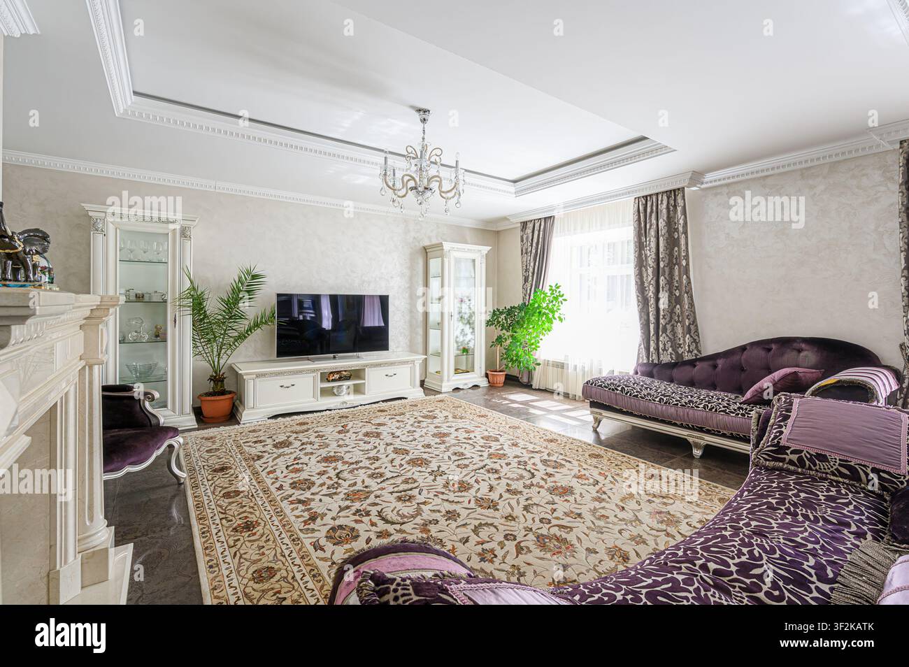 soggiorno lussuoso con mobili eleganti, un grande tappeto a motivi e un lampadario di cristallo Foto Stock