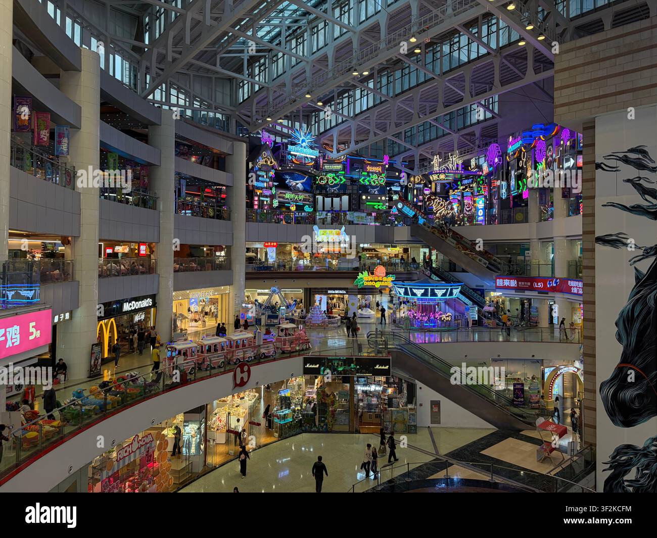 28 ottobre 2025, distretto di Tianhe, Guangzhou, Cina – Atrio di un centro commerciale a più livelli con luci al neon, scale mobili, McDonald's e negozi al dettaglio nella moderna Guangzhou. - Immagine stock catturata con smartphone