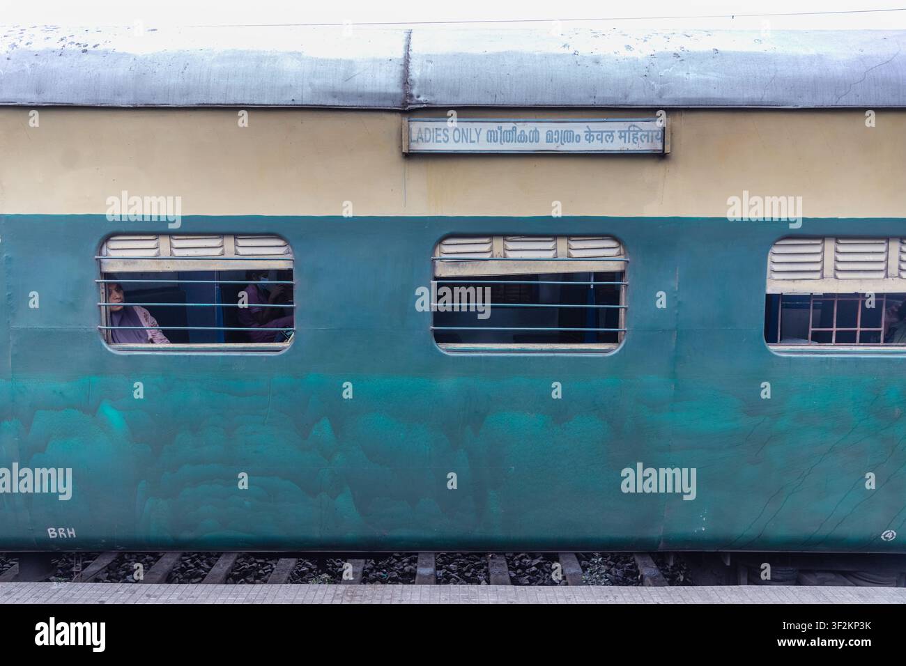 Vagone ferroviario blu solo per signore con passeggero visto attraverso il finestrino, evidenziando i trasporti pubblici nel Kerala, India. Foto Stock
