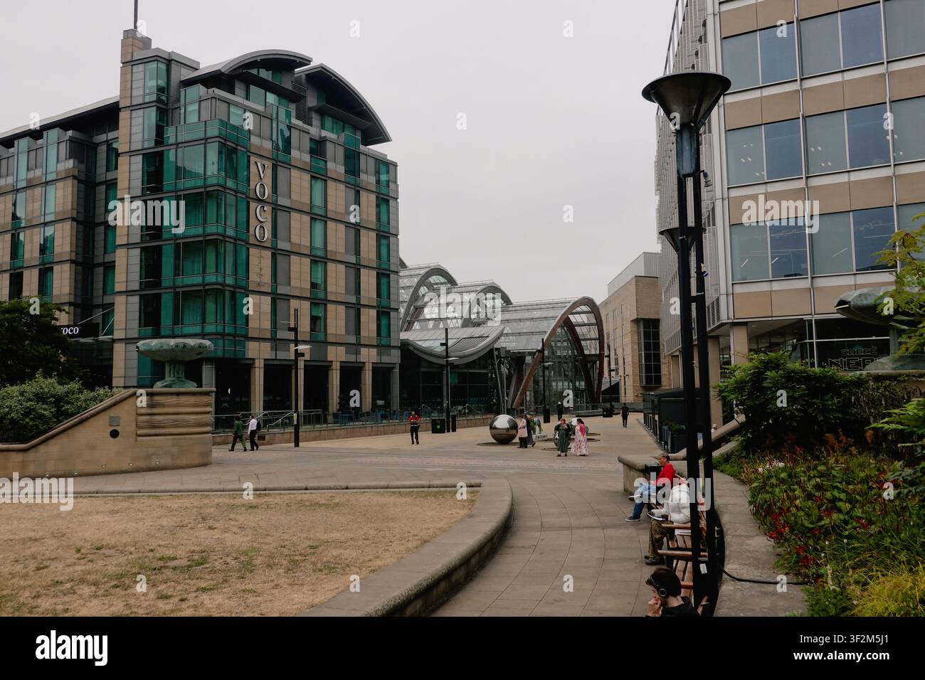 Pedoni che passano davanti al moderno hotel voco e all'architettura in vetro curva del Giardino d'Inverno a Sheffield, South Yorkshire, Inghilterra, Regno Unito. Foto Stock
