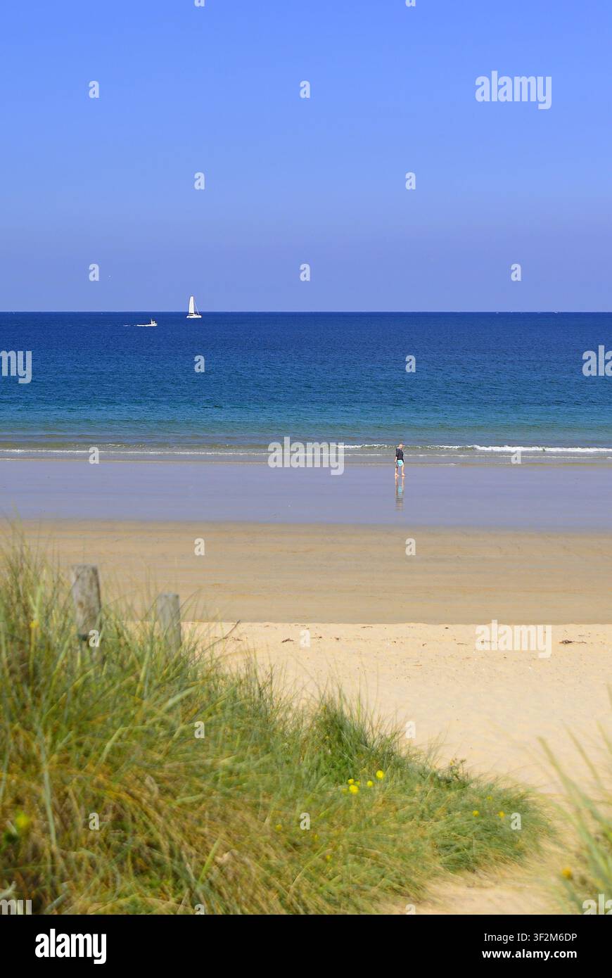 Una figura solitaria che passeggia lungo Praia America in una mattina di primavera con un cielo azzurro e temperature miti. Foto Stock