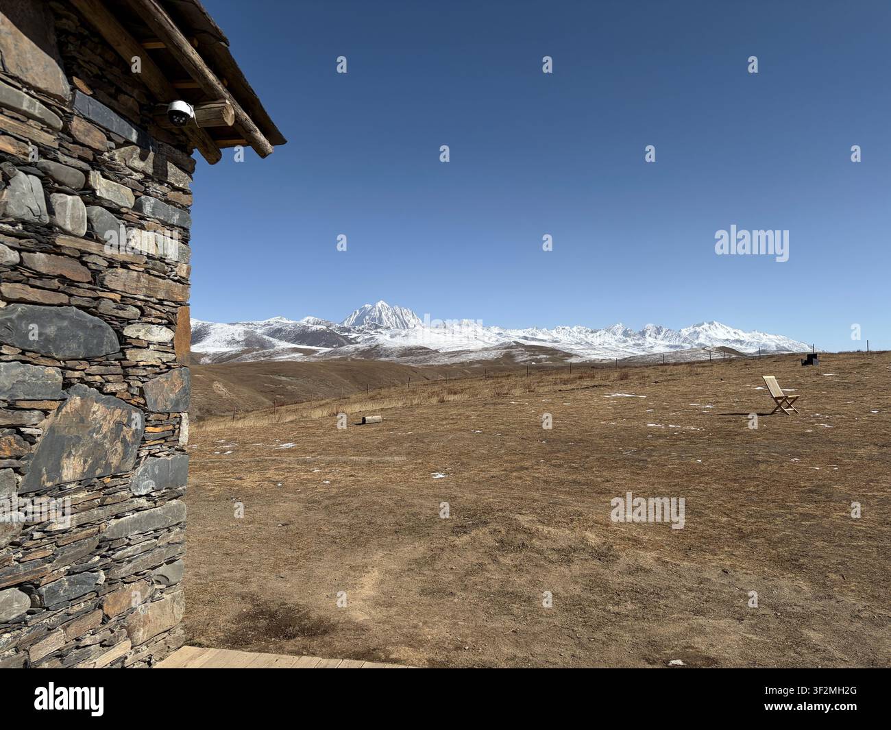 Edificio tradizionale in pietra con la cima innevata del monte Yala sullo sfondo sopra l'altopiano tibetano vicino a Kangding, Kardze, Sichuan, Cina. Foto Stock
