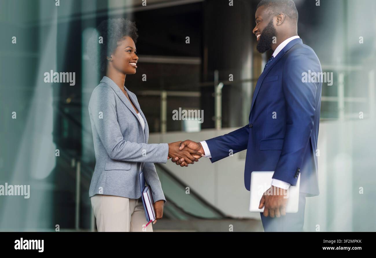 Incontro di lavoro tra due professionisti, uomo e donna afroamericani che si stringono la mano, ambiente d'ufficio Foto Stock