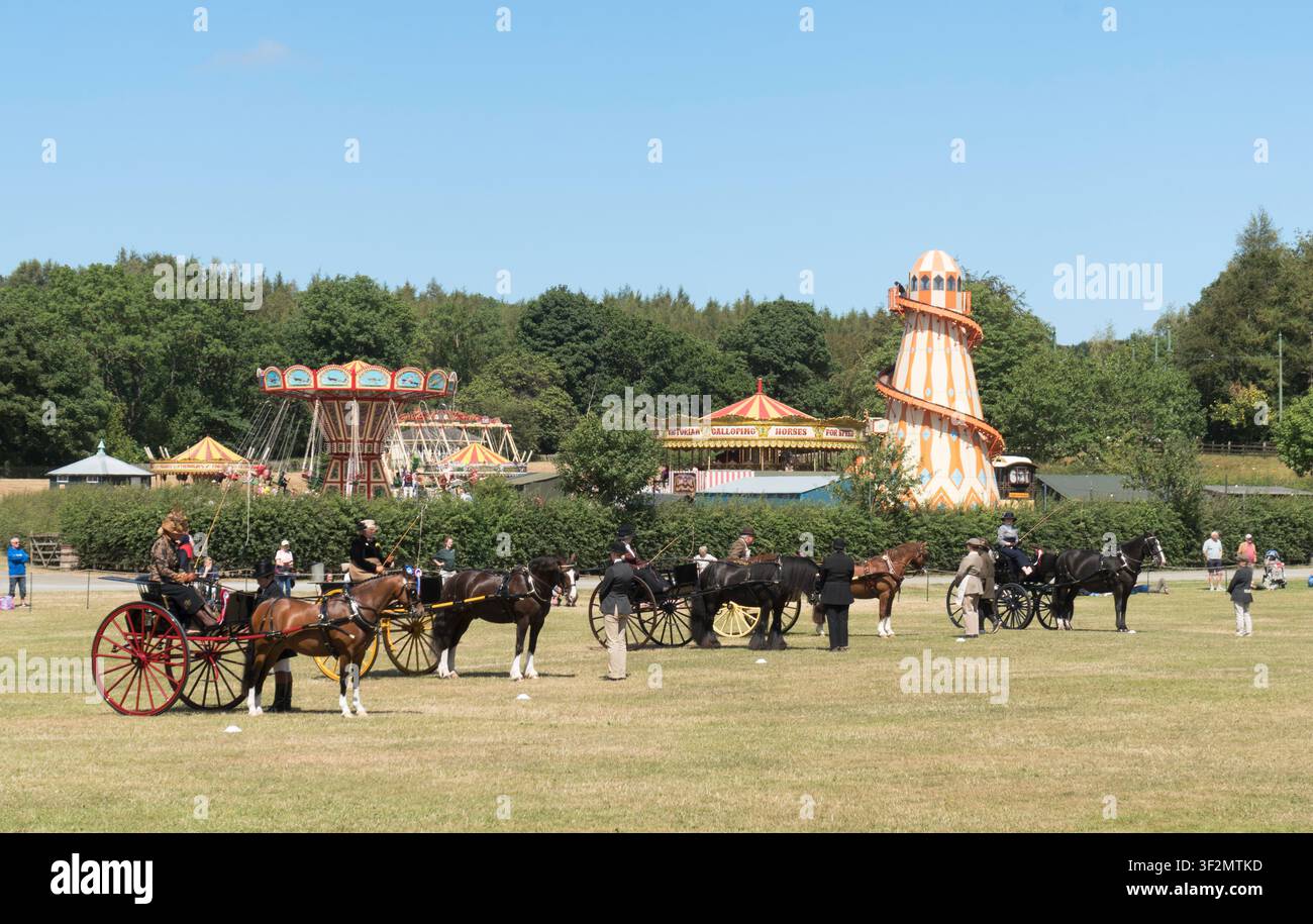 Una fila di carrozze al Beamish Museum durante il weekend Attelage horse con il luna park sullo sfondo, nord-est dell'Inghilterra, Regno Unito Foto Stock
