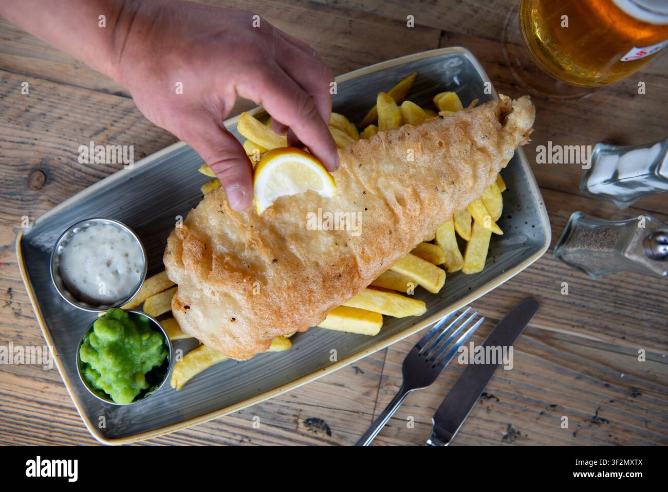 Pesce fritto dorato servito con patatine fritte croccanti e salsa da intingere Foto Stock