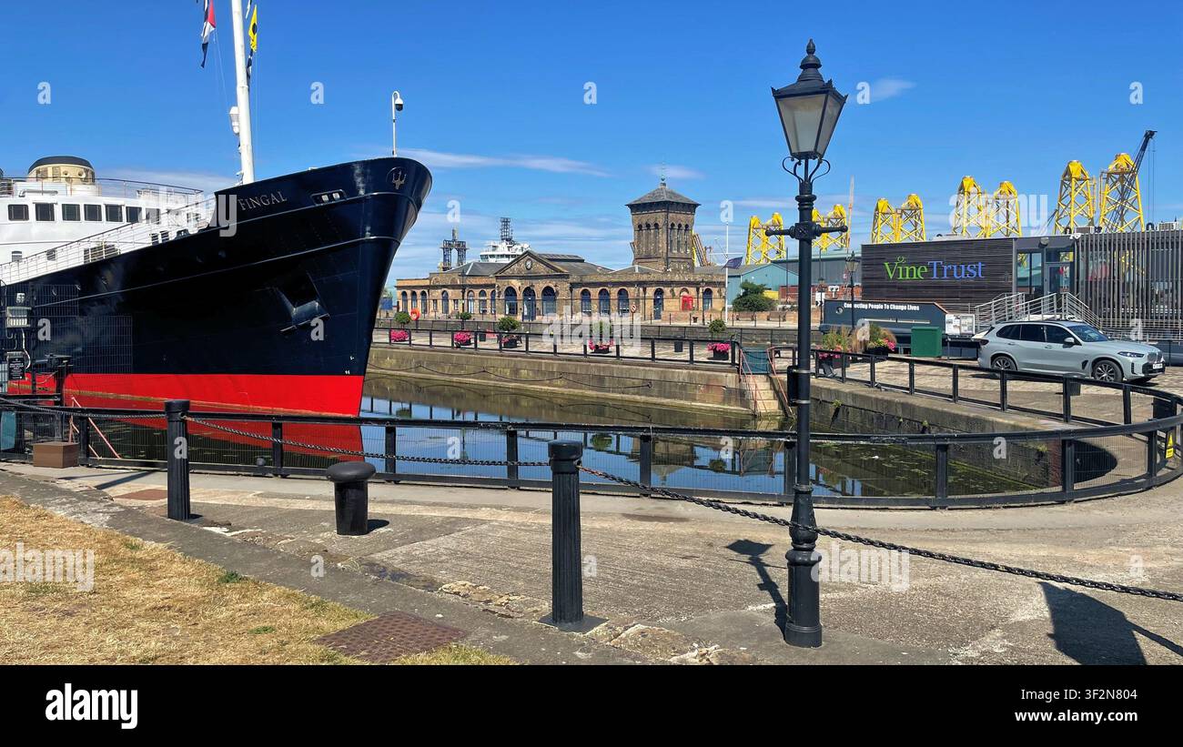 Fingal Hotel, un hotel galleggiante con strutture a torre a graticcio giallo che vengono fabbricate per un progetto eolico offshore sullo sfondo, Leith Edimburgo, Scozia - Immagine stock catturata con smartphone