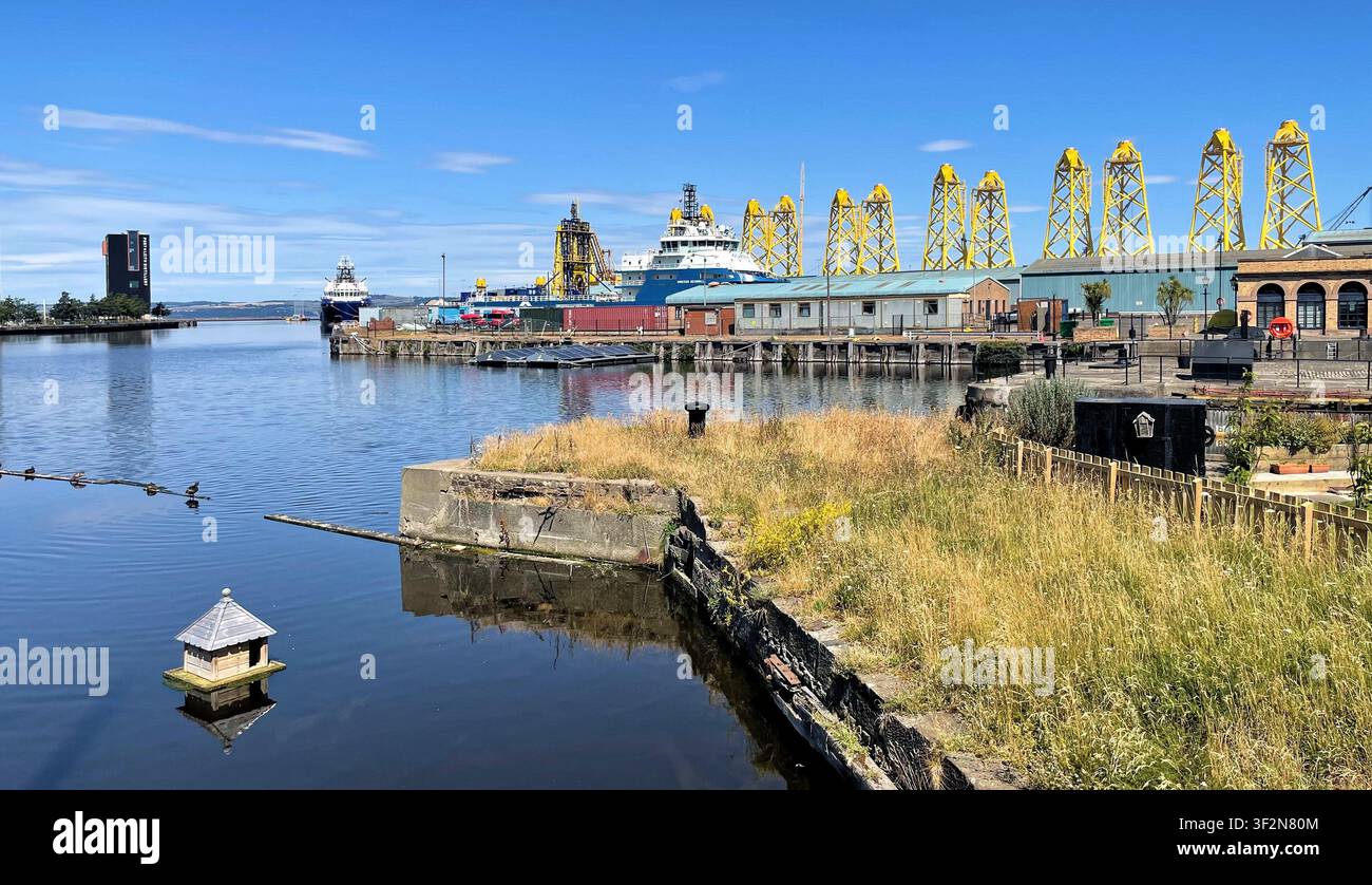 Strutture a torre a tre gambe gialle conosciute come fondazioni jacket in fase di fabbricazione per un progetto eolico offshore, moli di Leith a Edimburgo, Scozia - Immagine stock catturata con smartphone