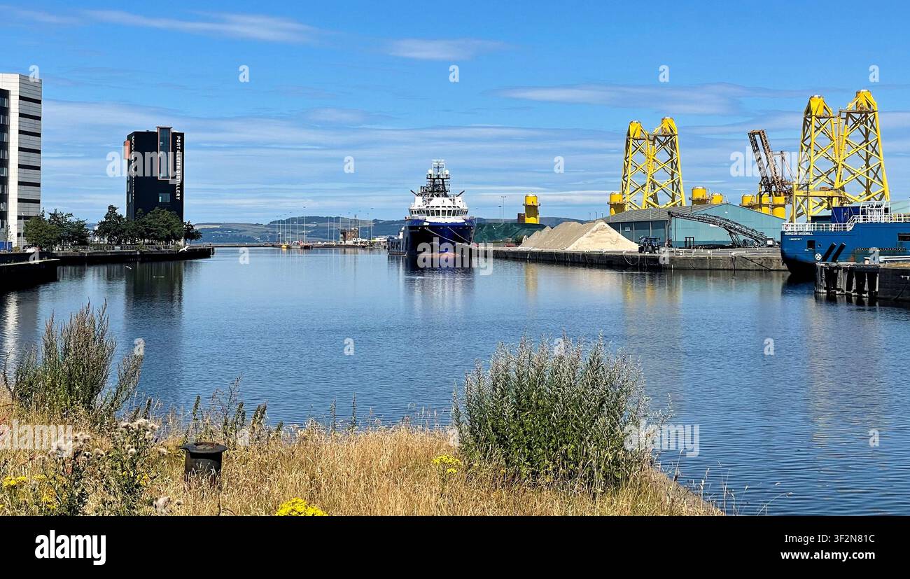 Strutture a torre a tre gambe gialle conosciute come fondazioni jacket in fase di fabbricazione per un progetto eolico offshore, moli di Leith a Edimburgo, Scozia - Immagine stock catturata con smartphone