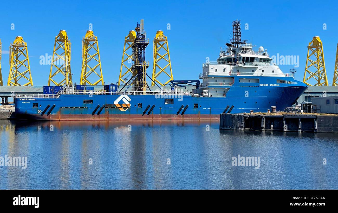 Strutture a torre a tre gambe gialle conosciute come fondazioni jacket in fase di fabbricazione per un progetto eolico offshore, moli di Leith a Edimburgo, Scozia - Immagine stock catturata con smartphone