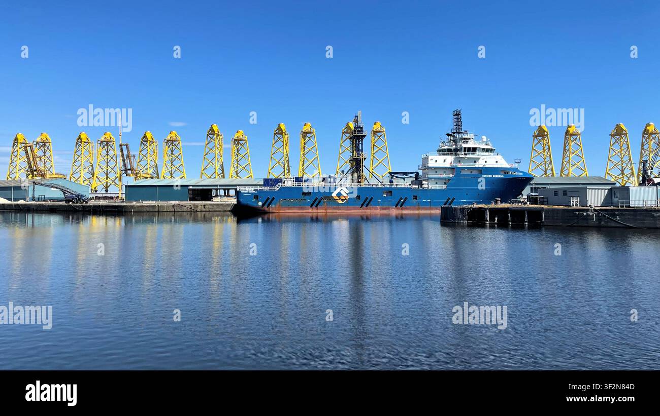Strutture a torre a tre gambe gialle conosciute come fondazioni jacket in fase di fabbricazione per un progetto eolico offshore, moli di Leith a Edimburgo, Scozia - Immagine stock catturata con smartphone