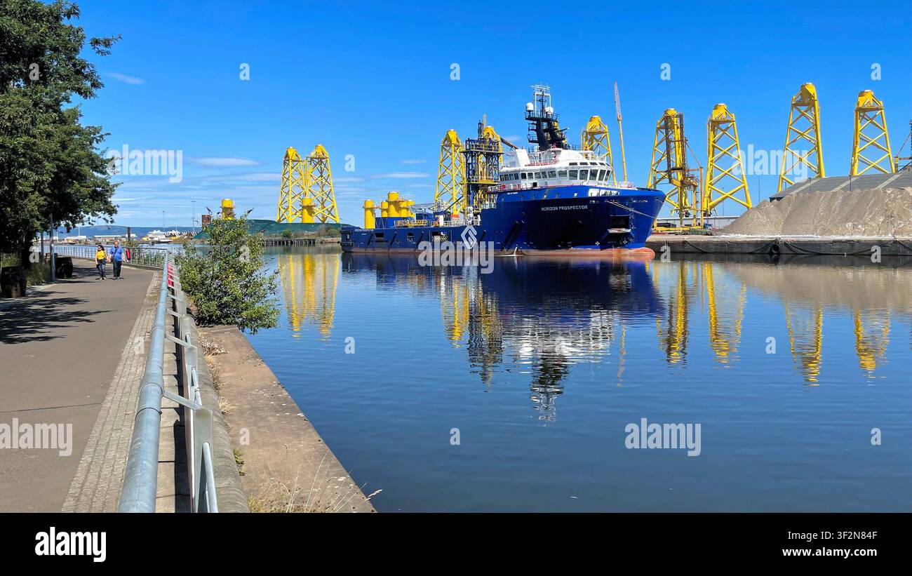 Strutture a torre a tre gambe gialle conosciute come fondazioni jacket in fase di fabbricazione per un progetto eolico offshore, moli di Leith a Edimburgo, Scozia - Immagine stock catturata con smartphone