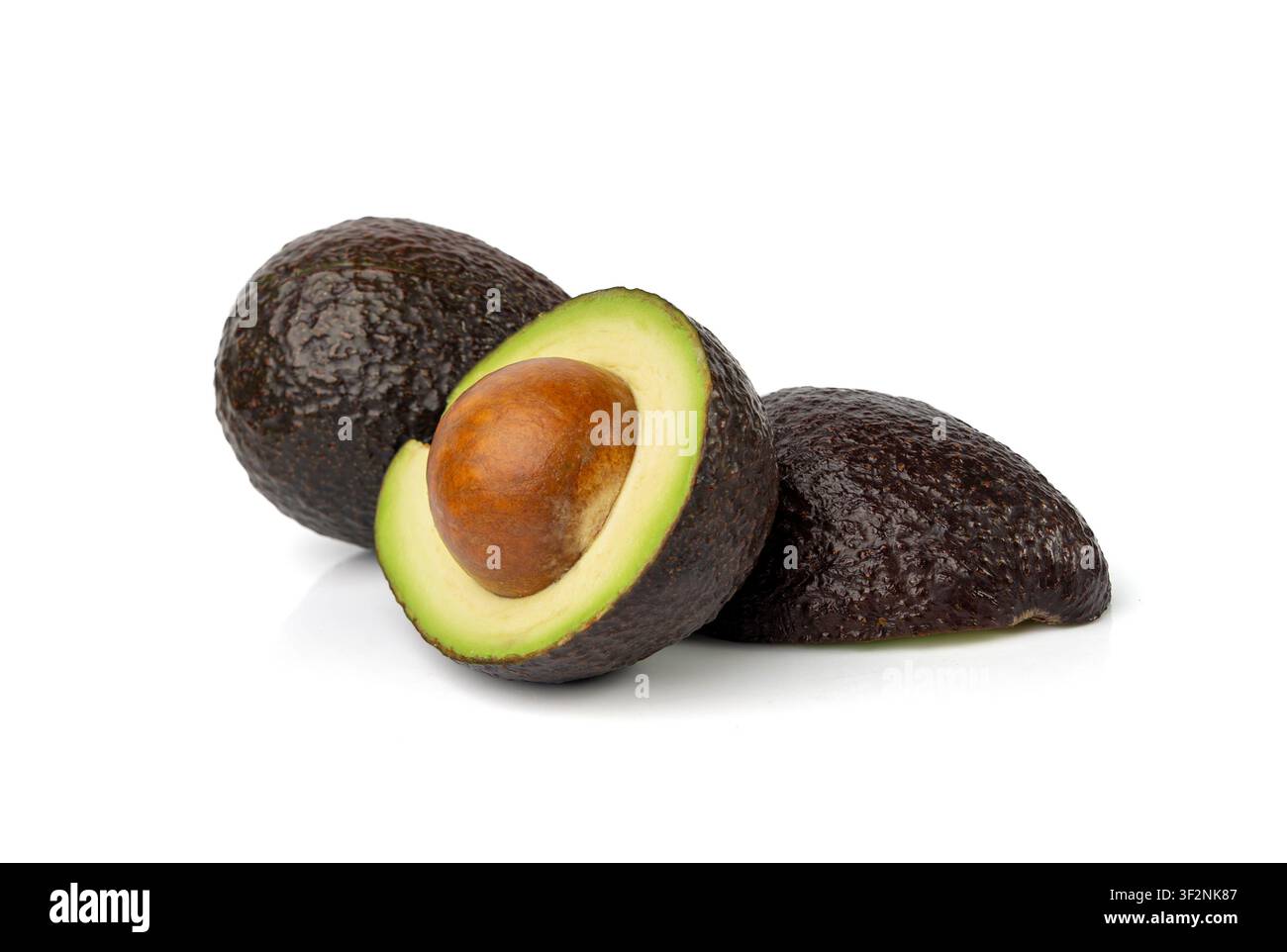 Mezza avocado Hass isolata, set completo Sharwil, avocado marroni tagliati, pera alligatore fresca, ingrediente per guacamole, frutto di avocado Persea americana su bianco Foto Stock