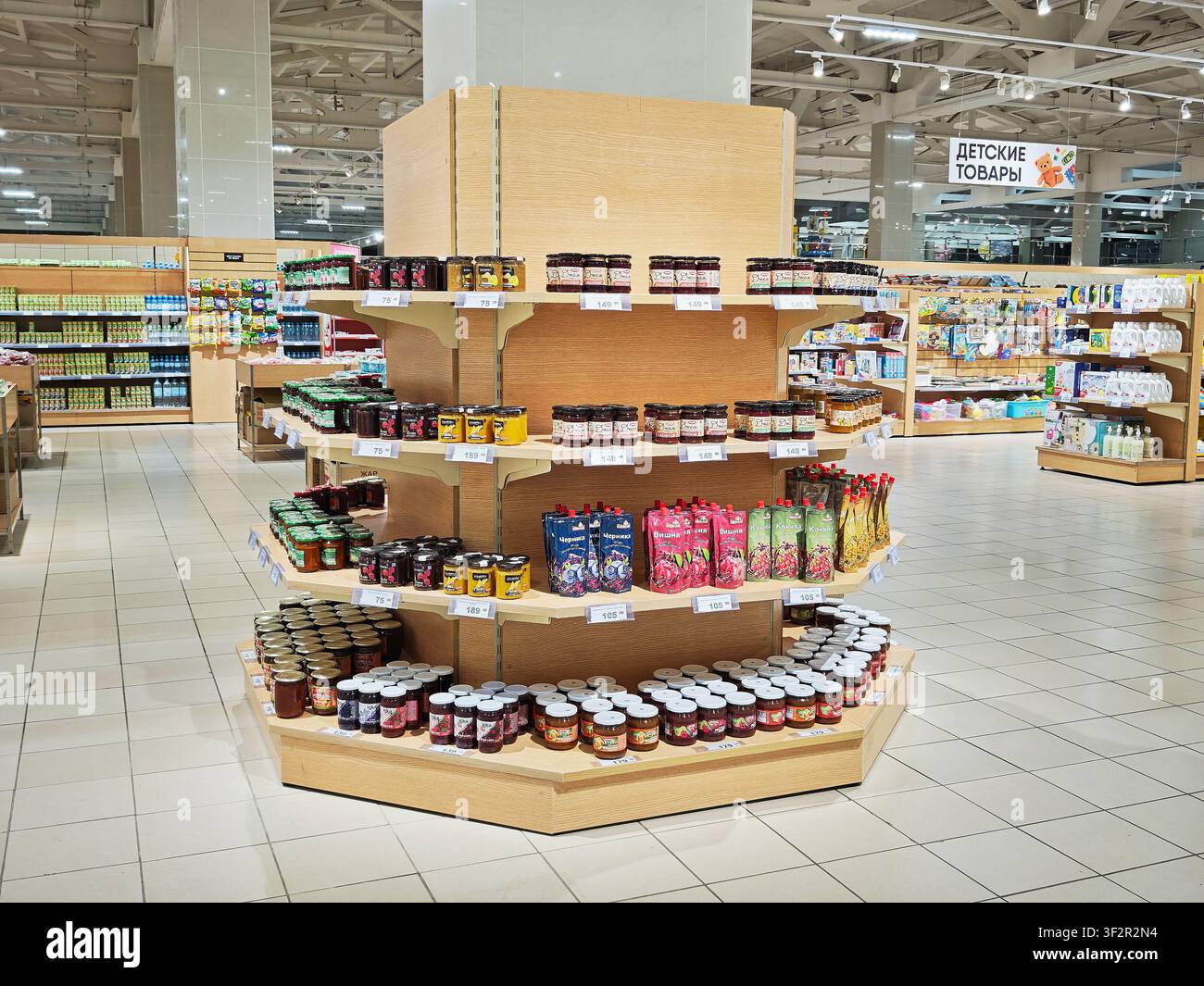 Kirov, Russia – 08 marzo 2026: I clienti sfogliano i corridoi del supermercato osservando diversi prodotti alimentari sugli scaffali mentre pianificano i loro acquisti di generi alimentari Foto Stock