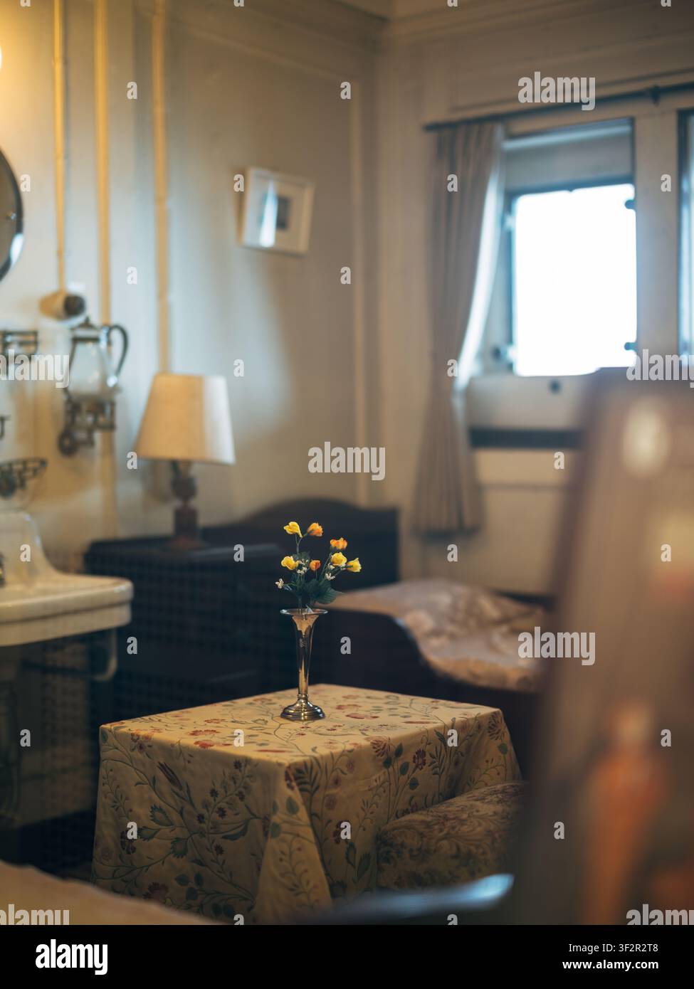 Accogliente cabina passeggeri di prima classe vintage con tovaglia floreale e letto all'interno della nave Hikawa Maru Foto Stock