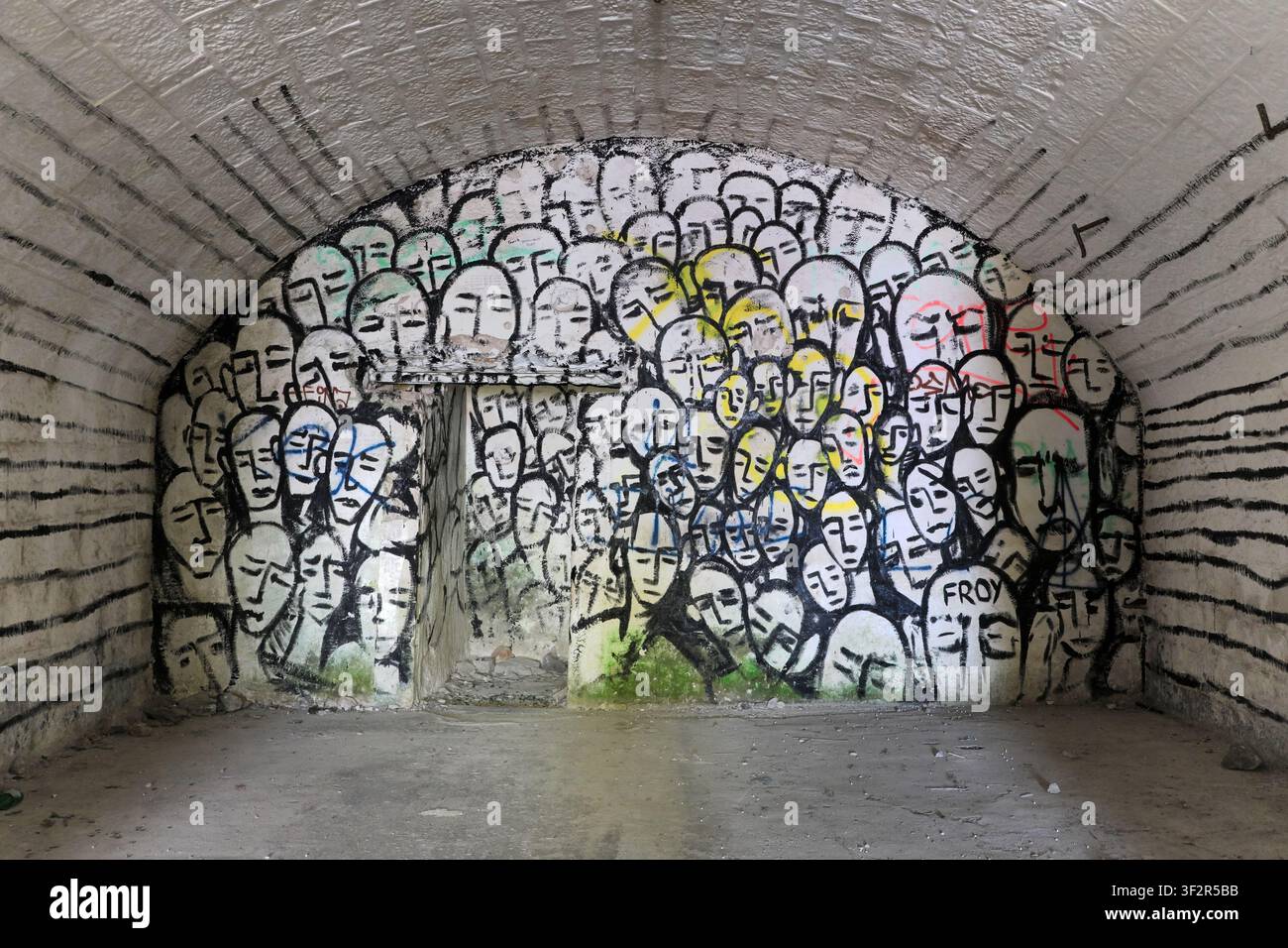 Affresco raffigurante teste collocate una accanto all'altra e ripetute in un edificio di cemento abbandonato Foto Stock