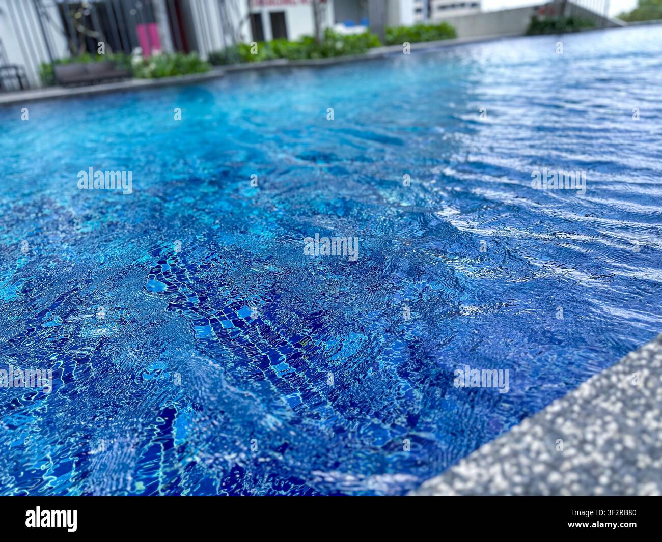 Onde sull'acqua blu vivace in una piscina all'aperto moderna di un edificio residenziale di lusso a Johor Bahru, Malesia. - Immagine stock catturata con smartphone