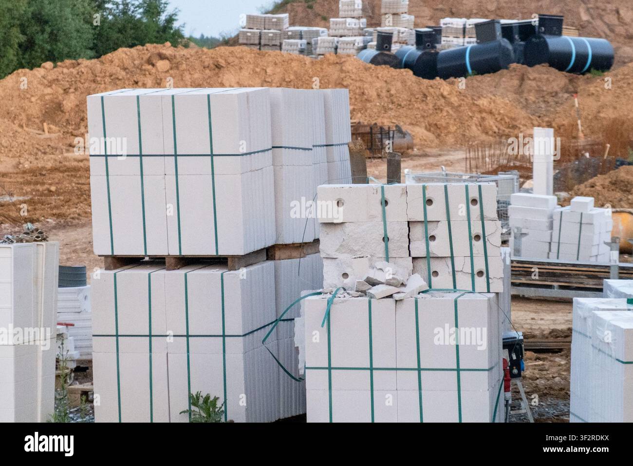 Blocchi di cemento disposti ordinatamente su bancali di legno in un cantiere edile. Adatti per documenti di pianificazione architettonica, presentazioni di ingegneria civile, proposte di progetti di costruzione. Foto Stock