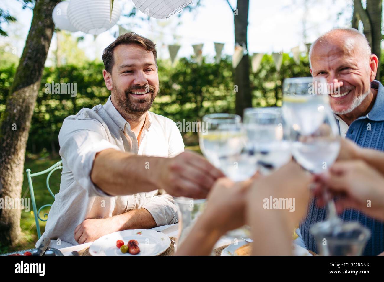 Brindisi multigenerazionali in famiglia durante una festa al barbecue all'aperto. Foto Stock